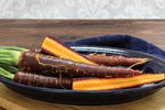freshly harvested purple carrots with earthy soil background

